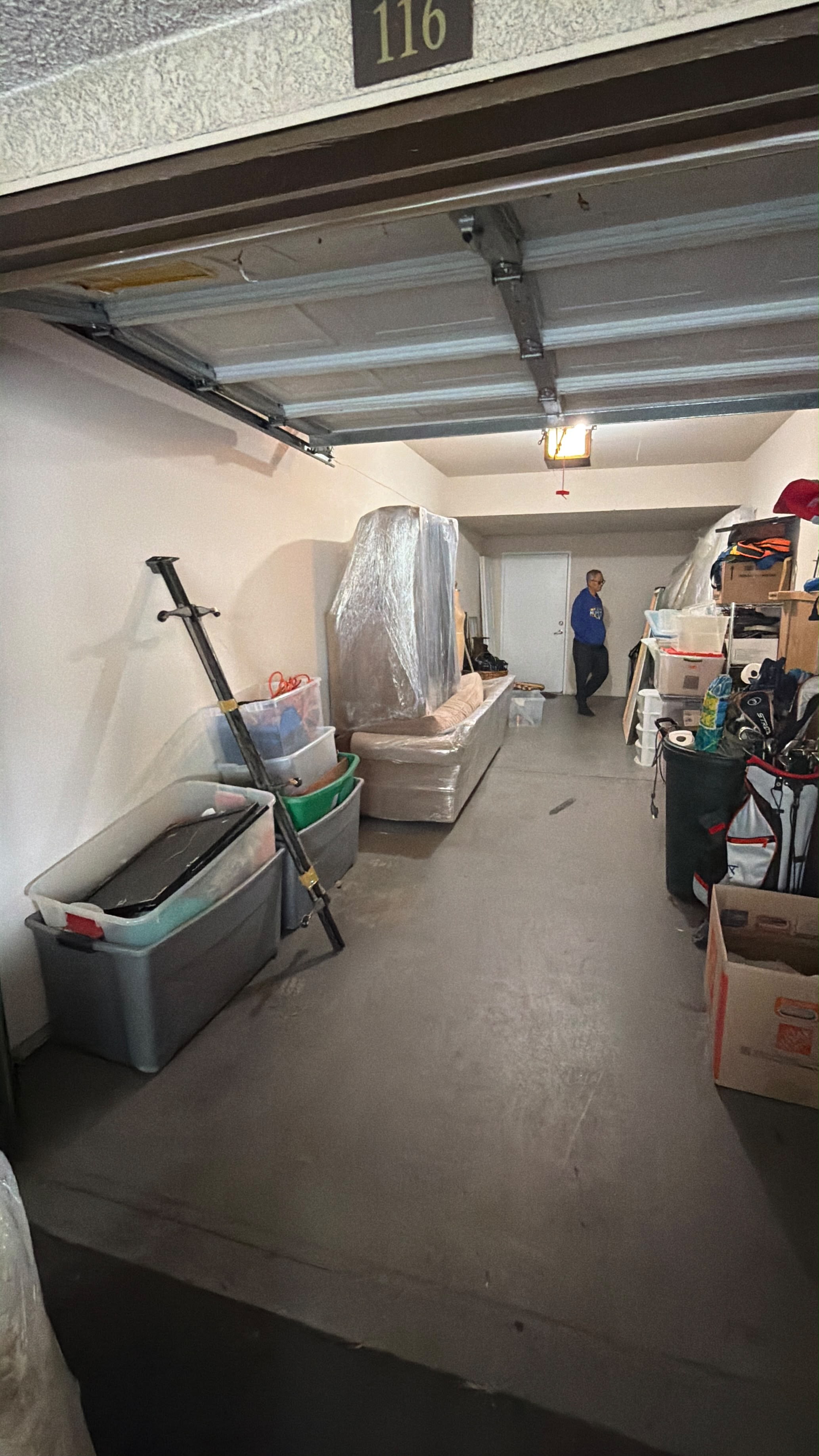 Open garage with boxed items, wrapped furniture, and a person standing inside